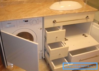 Amatérská fotka originální skříňky pod umyvadlem, která zahrnuje umístění mnoha zásuvek a domácích spotřebičů