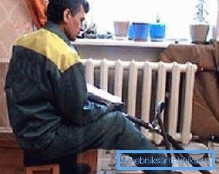 Na fotografii instalátor umývá radiátory v bytě Na fotografii instalátor umývá radiátory v bytě